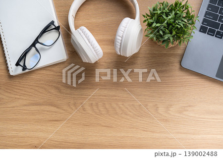 Peaceful Workspace with White Headphones, Glasses, Notebook, Green Plant, and Laptop on Wooden Desk for Creative or Study Environment Peaceful Workspace with White Headphones, Glasses, Notebook, Green Plant, and Laptop on Wooden Desk for Creative or Study Environment 139002488