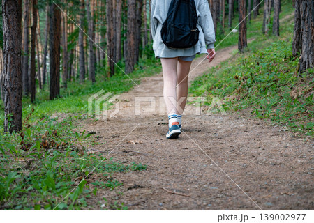 Person walking on a paved path through a forest with tall trees. Person walking on a paved path through a forest with tall trees. 139002977