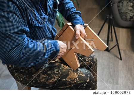 Man using power drill to assemble furniture in home setting during daytime Man using power drill to assemble furniture in home setting during daytime 139002978