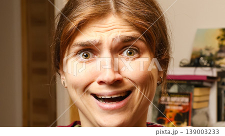 Close-up of a young woman face making a funny shocked or scared grimace with wide open eyes and mouth. Humorous facial expression concept. High detailed portrait Close-up of a young woman face making a funny shocked or scared grimace with wide open eyes and mouth. Humorous facial expression concept. High detailed portrait 139003233