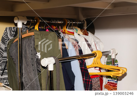 Close-up of various clothes hanging on a metal garment rack in a wardrobe. Organized clothing on hangers in a domestic interior or retail store 139003246
