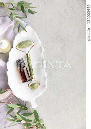 Jade Facial Roller and Essential Oil Bottle on White Dish Jade Facial Roller and Essential Oil Bottle on White Dish 139003486