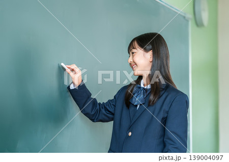 教室の黒板にチョークで文字を書く中学生の女子生徒 教室の黒板にチョークで文字を書く中学生の女子生徒 139004097