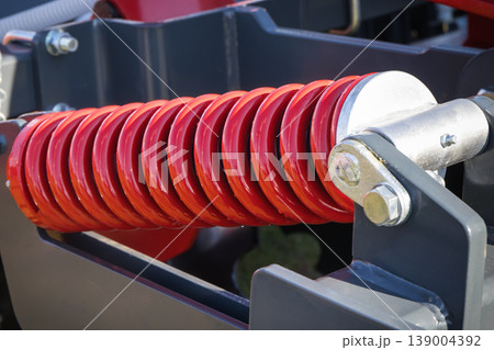 Steel red spring as part of black heavy agricultural, industrial machine. Technology Steel red spring as part of black heavy agricultural, industrial machine. Technology 139004392