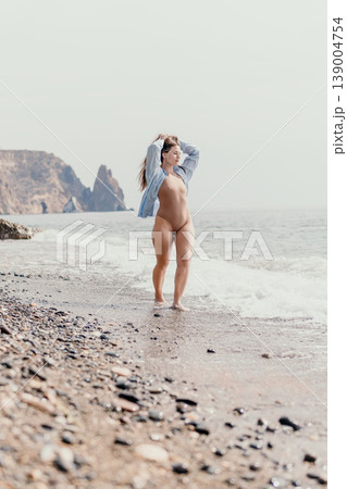 Woman beach swimsuit young female in beige bodysuit walking on pebbled shore by the sea with rocky cliffs under a bright sky Woman beach swimsuit young female in beige bodysuit walking on pebbled shore by the sea with rocky cliffs under a bright sky 139004754