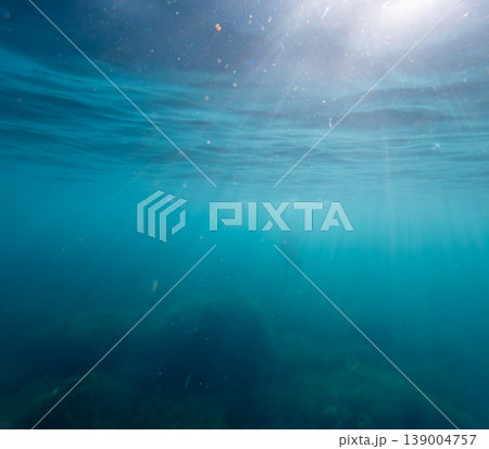 Underwater sunbeams ocean scene showing light rays filtering through the surface of deep blue water for a tranquil and mysterious atmosphere Underwater sunbeams ocean scene showing light rays filtering through the surface of deep blue water for a tranquil and mysterious atmosphere 139004757