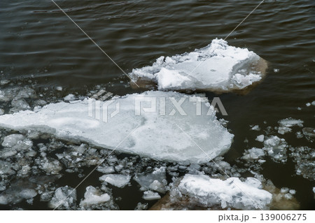 Melting Ice Floes on Dark Water Surface During Winter Thaw Near Shoreline 139006275