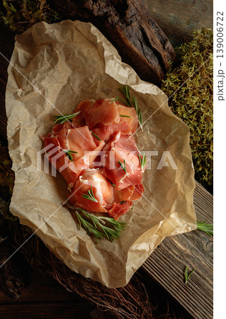 Prosciutto slices with rosemary wrapped in paper. 139006722