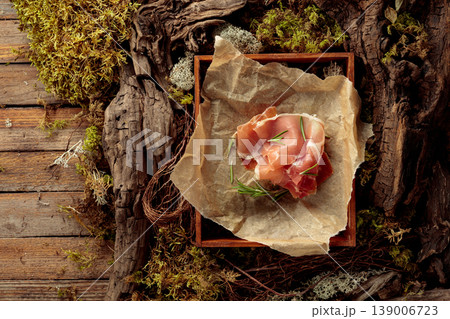 Prosciutto with rosemary on a paper in wooden box. 139006723