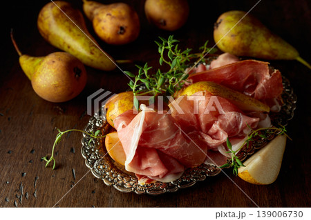 Prosciutto with pears and thyme on a silver tray. 139006730