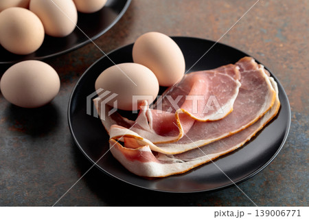 Smoked pork bacon with eggs on a black plate. Smoked pork bacon with eggs on a black plate. 139006771