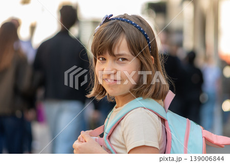 Girl 7 years old walking with backpack looking back in urban scene Girl 7 years old walking with backpack looking back in urban scene 139006844
