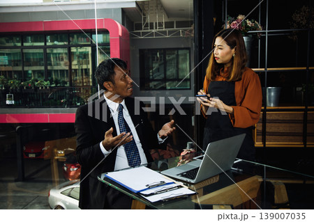 Businessman discussing order with waitress in cafe, customer service problem solving concept, showing communication, negotiation and professional interaction in modern restaurant environment 139007035