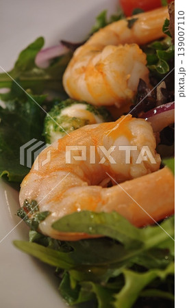 Fresh shrimp placed on a bed of mixed greens with colorful vegetables, showcasing the vibrant textures and colors of a nutritious seafood salad 139007110