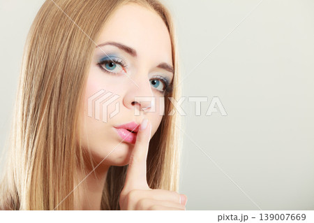 Woman asking for silence finger on lips Woman asking for silence finger on lips 139007669