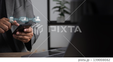 Close-up of a hand using a smartphone with delivery tracking icons in a home workspace, representing online shopping, mobile ordering, and logistics service usage. Close-up of a hand using a smartphone with delivery tracking icons in a home workspace, representing online shopping, mobile ordering, and logistics service usage. 139008082