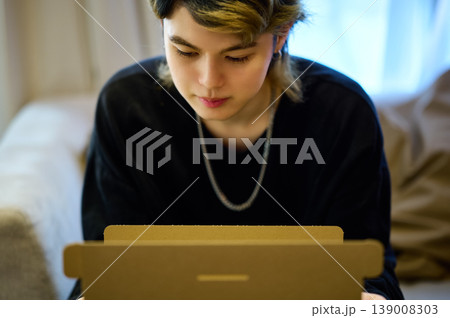 自宅で届いた荷物を開封し中身を覗き込むZ世代の男性 139008303