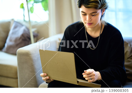 リビングのソファでリラックスしながらタブレットを操作するZ世代の若い男性 139008305