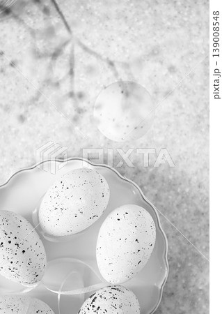 Minimal white speckled Easter eggs on a ceramic plate with soft textured background 139008548