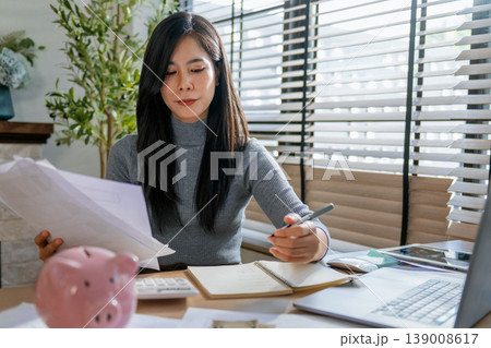 Woman sits at desk, focused on finances Woman sits at desk, focused on finances 139008617