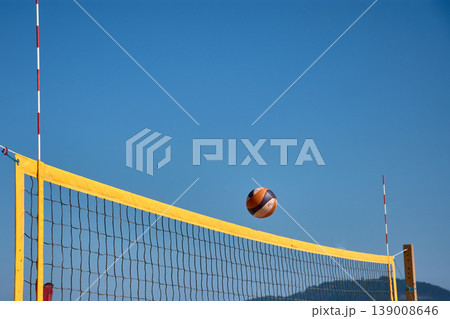 Volleyball in the air over a yellow net during a beach match in Baiona under a clear blue sky Volleyball in the air over a yellow net during a beach match in Baiona under a clear blue sky 139008646