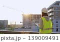 Construction female engineer taking notes and tapping on tablet computer while inspecting a building site at sunset. Industry development concept 139009491