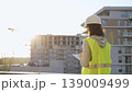 Woman construction engineer is taking notes with a tablet pc while inspecting a construction site at sunset 139009499