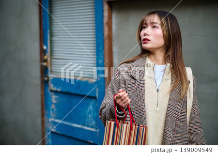 ショッピングバッグを持って街角に立つお洒落な日本人女性 ショッピングバッグを持って街角に立つお洒落な日本人女性 139009549
