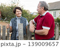 Positive mature man and woman standing near fence in garden 139009657