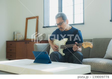 ソファーでギターを弾くシニア男性 139009778