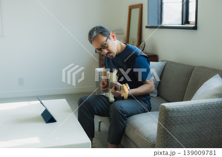 ソファーでギターを弾くシニア男性 139009781