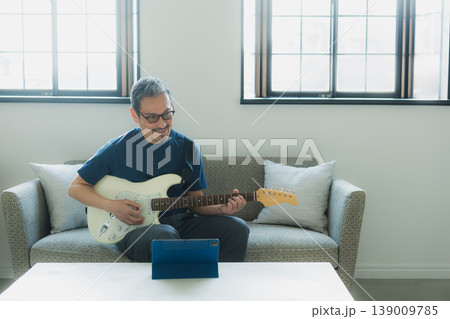 ソファーでギターを弾くシニア男性 139009785