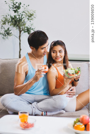 A happy couple prepares fresh vegetables, laughing and enjoying cooking a healthy meal together. A happy couple prepares fresh vegetables, laughing and enjoying cooking a healthy meal together. 139009850