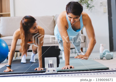 Support, teamwork and fitness couple doing workout training, challenging exercise for endurance, strength and stamina in a gym. Active, fit man and woman giving support and motivation during pushup Support, teamwork and fitness couple doing workout training, challenging exercise for endurance, strength and stamina in a gym. Active, fit man and woman giving support and motivation during pushup 139009871