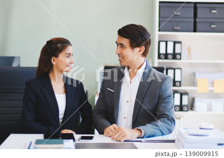 Portrait of a happy Asian business couple standing together. Young professional man and woman smiling in studio. Corporate teamwork concept Portrait of a happy Asian business couple standing together. Young professional man and woman smiling in studio. Corporate teamwork concept 139009915