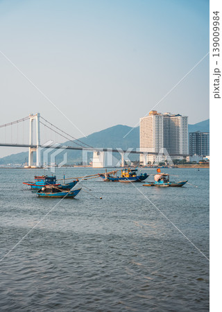 Fishing boats on Han river with Cau Thuan Phuoc bridge and city skyline at sunset in Da Nang, Traditional fisherman vessels on Golden Gate, calm water and mountains background, Danang Vietnam 4k 139009984