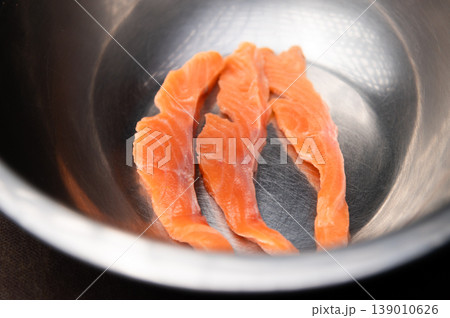 Fresh salmon fillets arranged in a stainless steel bowl on a dark surface Fresh salmon fillets arranged in a stainless steel bowl on a dark surface 139010626