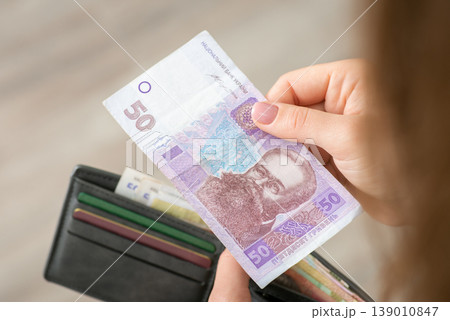 Female paying for something with 50 hryvnia. Hryvnia banknote and a purse in hands of a girl Female paying for something with 50 hryvnia. Hryvnia banknote and a purse in hands of a girl 139010847