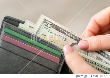 Close up of a woman counting dollar money in purse. 5 dollar banknote in wallet of a person Close up of a woman counting dollar money in purse. 5 dollar banknote in wallet of a person 139010848