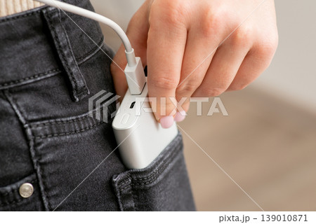 Power bank in the back pocket of girl's jeans, close up. Concept of using modern technologies, charging gadgets, convenient and portable devices 139010871
