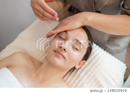 Beautiful young woman enjoying face massage during beauty treatment in the spa, close up. Beauty procedure, relaxation, skin and health care concepts Beautiful young woman enjoying face massage during beauty treatment in the spa, close up. Beauty procedure, relaxation, skin and health care concepts 139010919
