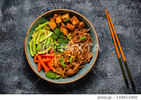 Soba noodles with vegetables and fried tofu in a bowl. Soba noodles with vegetables and fried tofu in a bowl. 139011000