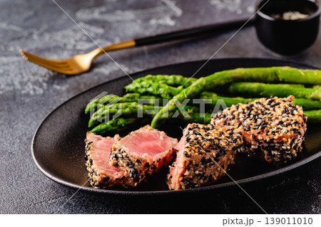Tuna steak fried in sesame seeds served with asparagus. Tuna steak fried in sesame seeds served with asparagus. 139011010