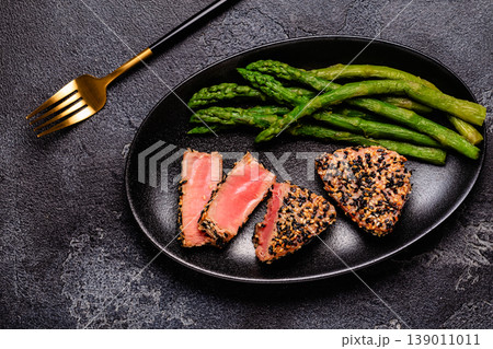 Tuna steak fried in sesame seeds served with asparagus. Tuna steak fried in sesame seeds served with asparagus. 139011011