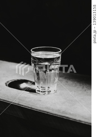 Glass of still water on a dark background. Black and white photography. Minimal concept. Glass of still water on a dark background. Black and white photography. Minimal concept. 139013158