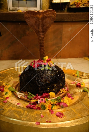 Black Stone Shiva Lingam Decorated with Marigold and Roses under Metallic Cobra 139013183
