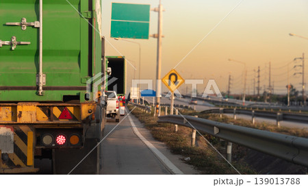 Back of a green shipping container as it drives along a congested parallel road. with turn on brake light. Various traffic signs are visible including U turn signs at the interchange ahead. Back of a green shipping container as it drives along a congested parallel road. with turn on brake light. Various traffic signs are visible including U turn signs at the interchange ahead. 139013788