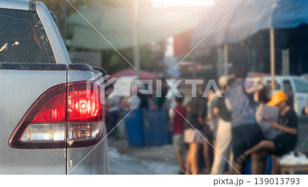 Rear side view of pickup car with turn on brake light. Blurred of other people standing on the ground side of road for playing Songkran Festival in Thailand. 139013793