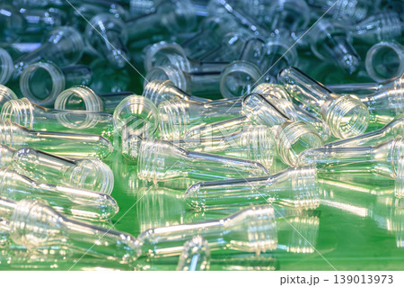 Close-up of clear PET preforms on an automated conveyor belt system from a plastic injection machine. Close-up of clear PET preforms on an automated conveyor belt system from a plastic injection machine. 139013973