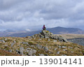 Hiker sitting on mountain peak enjoying vista 139014141